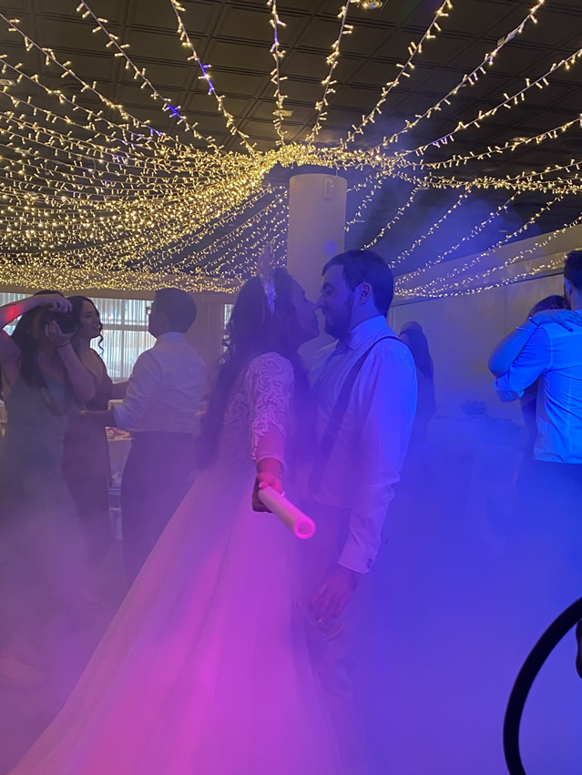 Pareja bailando bajo las luces durante la boda