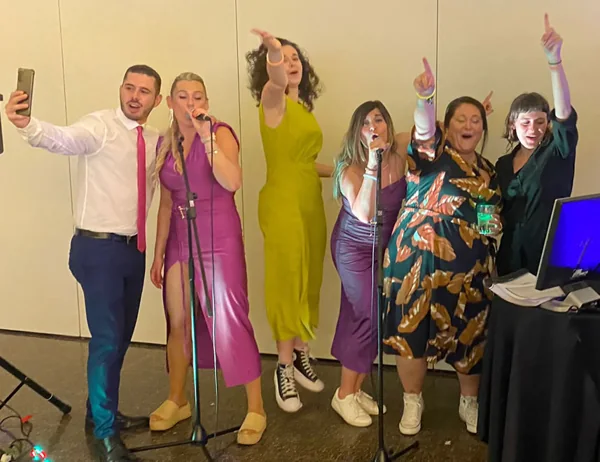 Un grupo de invitados cantando juntos con micrófonos durante una boda